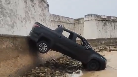 Carro ficou inclinado perigosamente sobre o muro - Foto: Reprodução