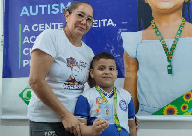 Mãe com seu filho utilizando o cordão de girassol para identificação de pessoas com condições ocultas, que não são visíveis fisicamente.